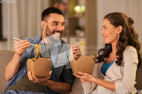 Image of happy couple eating takeaway noodles at home