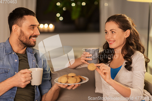 Image of happy couple drinking tea with cookies at home