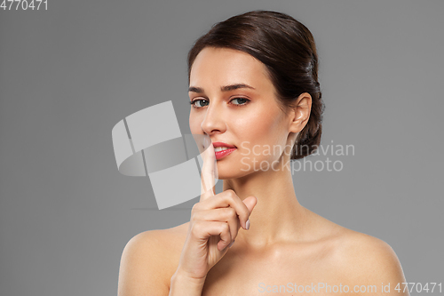 Image of beautiful young woman holding finger on lips