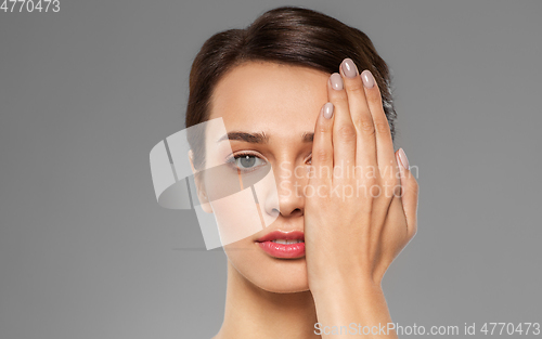 Image of young woman closing one eye with hand