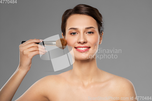 Image of beautiful woman with makeup brush applying blusher