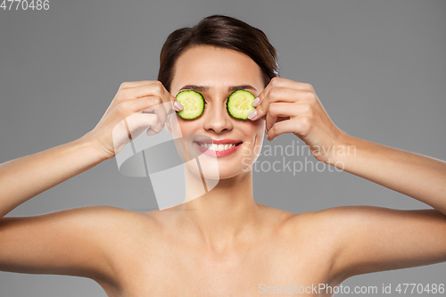 Image of beautiful woman making eye mask of cucumbers