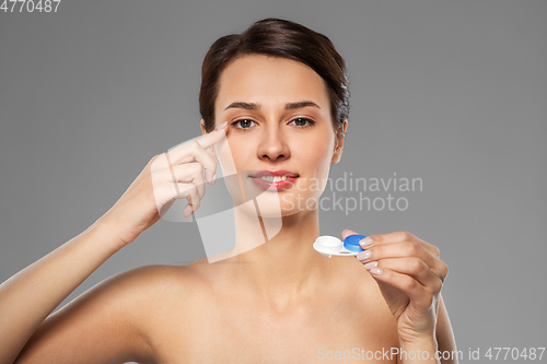 Image of happy young woman applying contact lenses