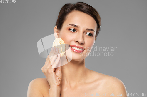 Image of young woman cleaning face with exfoliating sponge