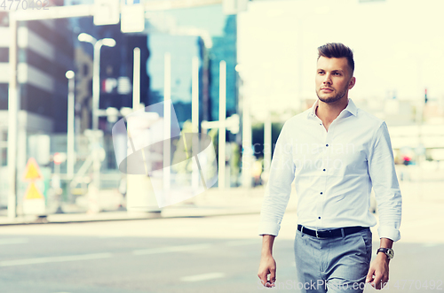 Image of young man walking along city street