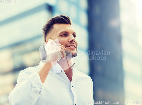 Image of happy man with smartphone calling on city street