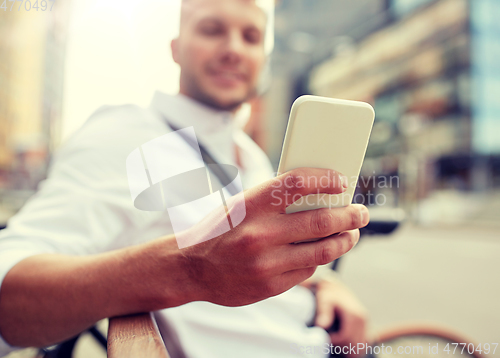 Image of close up of man texting on smartphone in city