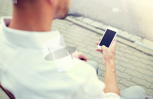 Image of close up of man texting on smartphone in city