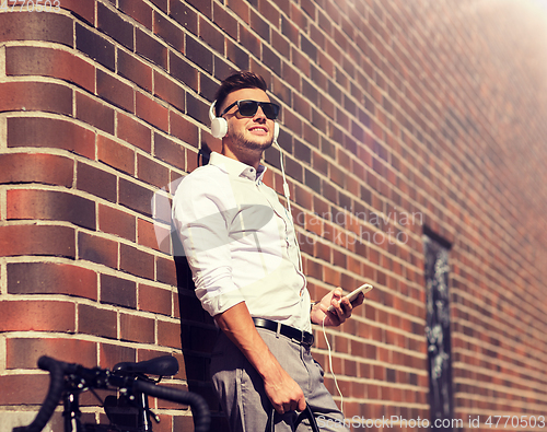 Image of man with headphones, smartphone and bicycle