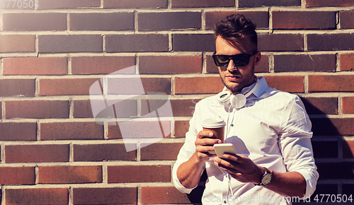 Image of man with smartphone and coffee cup on city street