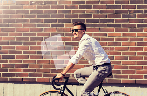 Image of young man riding bicycle on city street