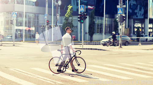 Image of young man with bicycle on crosswalk in city