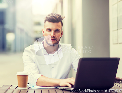 Image of man with laptop and coffee at city cafe