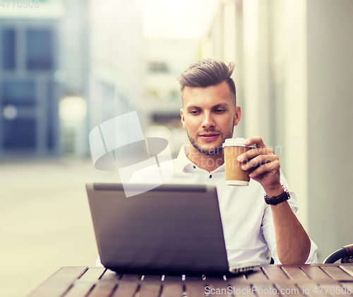 Image of man with laptop and coffee at city cafe