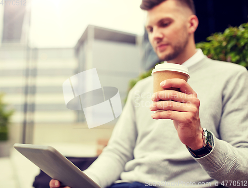 Image of man with tablet pc and coffee cup on city street