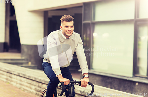 Image of young man riding bicycle on city street