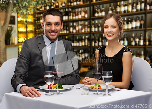 Image of smiling couple with food and wine at restaurant