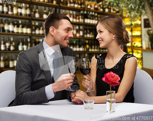 Image of happy couple drinking red wine at restaurant