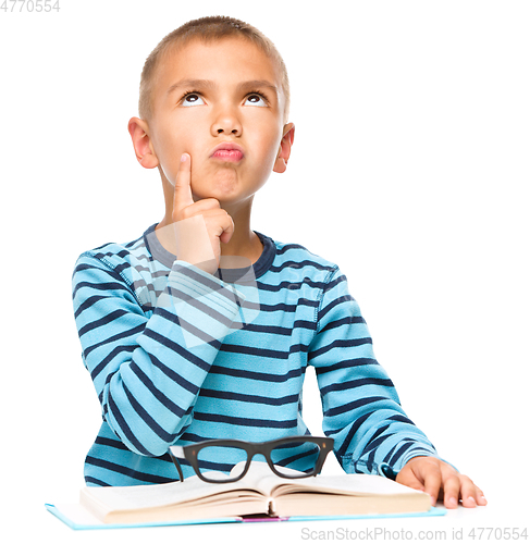 Image of Young boy is daydreaming while reading book