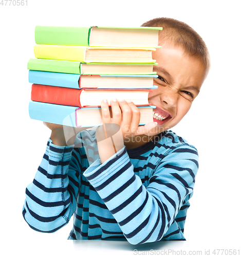 Image of Little boy is holding a pile of books