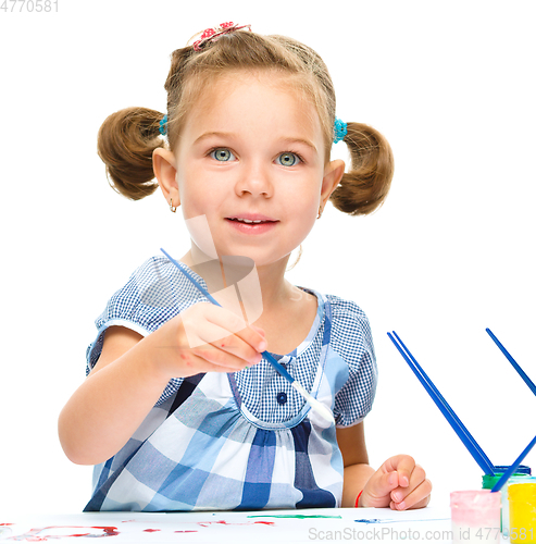 Image of Little girl is painting with gouache