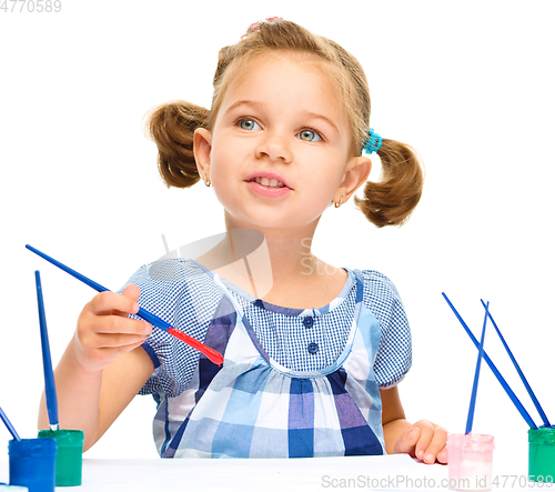 Image of Little girl is painting with gouache