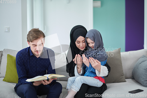 Image of Young muslim family reading Quran during Ramadan
