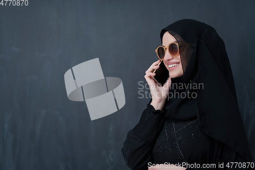 Image of Young muslim businesswoman in traditional clothes or abaya using smartphone