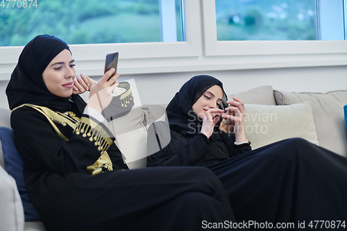 Image of Portrait of Arabian girls wearing modern abaya using mobile phone