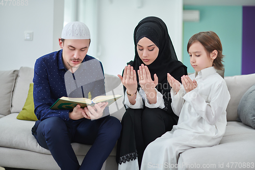 Image of Young muslim family reading Quran during Ramadan