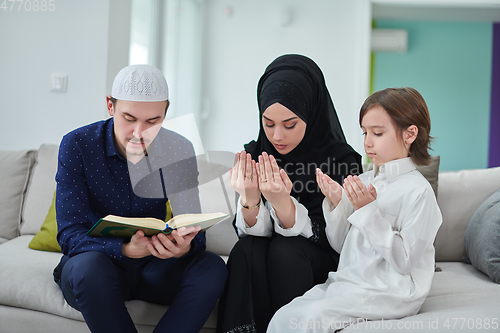 Image of Young muslim family reading Quran during Ramadan