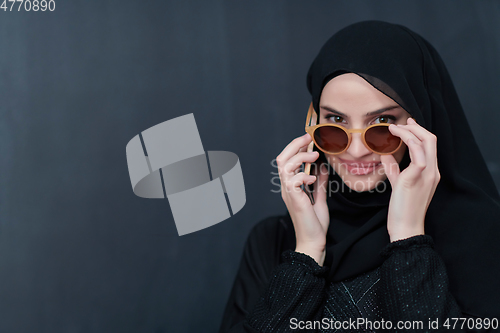 Image of Young muslim businesswoman in traditional clothes or abaya using smartphone