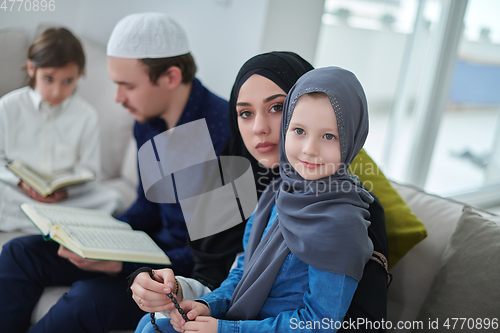 Image of Young muslim family reading Quran during Ramadan