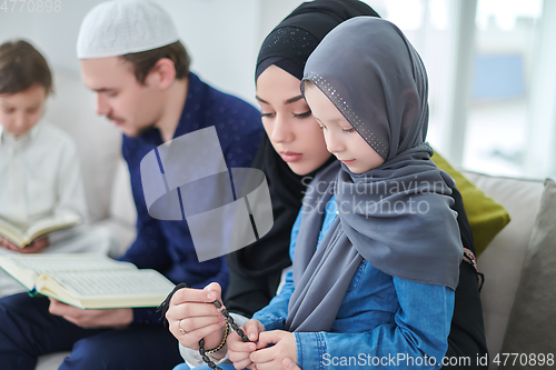 Image of Young muslim family reading Quran during Ramadan