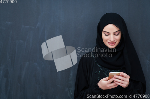 Image of Young muslim businesswoman in traditional clothes or abaya using smartphone