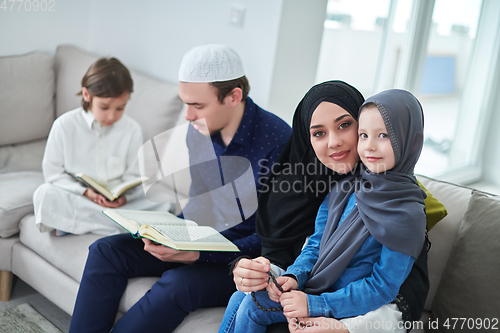 Image of Young muslim family reading Quran during Ramadan