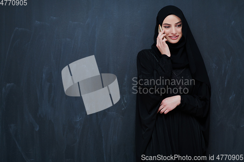 Image of Young muslim businesswoman in traditional clothes or abaya using smartphone