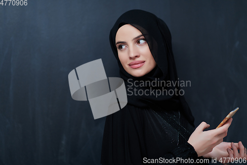 Image of Young muslim businesswoman in traditional clothes or abaya using smartphone