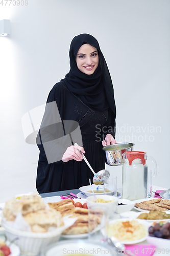 Image of Young muslim woman serving food for iftar during Ramadan