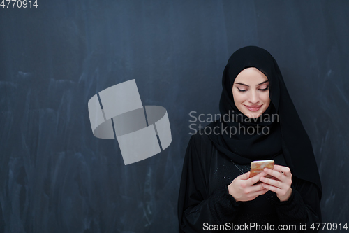 Image of Young muslim businesswoman in traditional clothes or abaya using smartphone