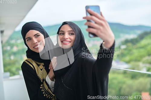 Image of Portrait of young muslim women taking selfie on the balcony