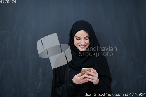 Image of Young muslim businesswoman in traditional clothes or abaya using smartphone