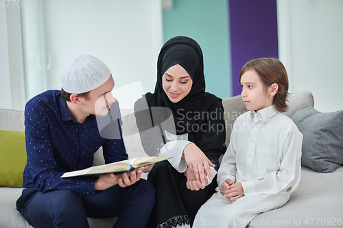 Image of Young muslim family reading Quran during Ramadan