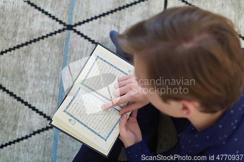 Image of Young muslim man reading Quran during Ramadan