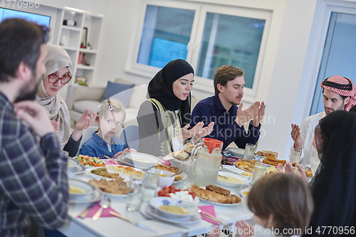 Image of Muslim family making iftar dua to break fasting during Ramadan.