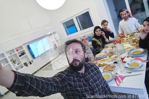 Image of Muslim family taking selfie while having iftar together during Ramadan