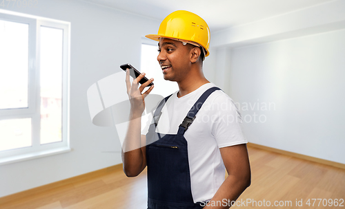 Image of happy indian builder recording voice on smartphone