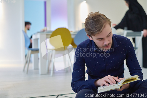 Image of Young muslim man reading Quran during Ramadan