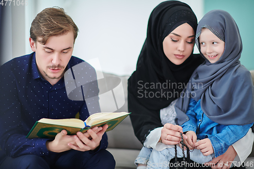 Image of Young muslim family reading Quran during Ramadan