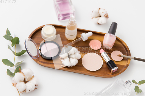 Image of makeup, perfume and cosmetics on wooden tray